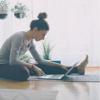 Woman using laptop and doing yoga